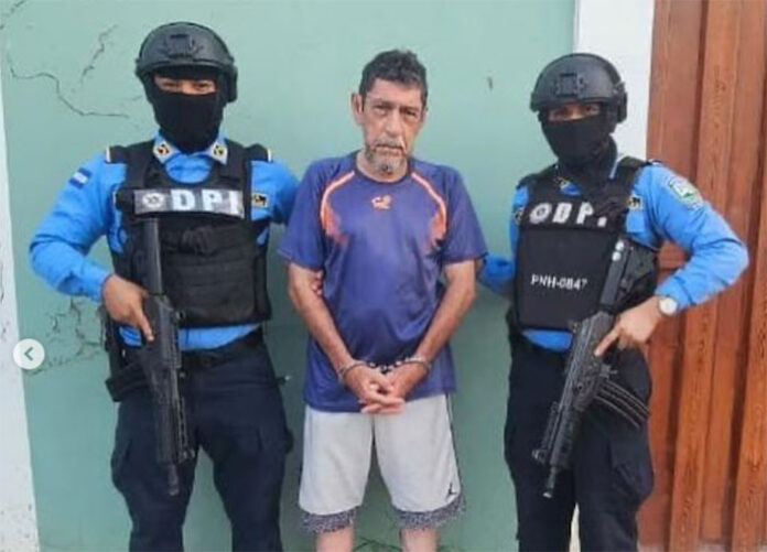 Perfecto Jesús Enamorado flanqueado por dos agentes de la Dirección Policial de Investigaciones (DPI). Imagen de redes sociales, el día de su captura. Foto: cortesía Proceso Digital